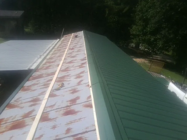Old rusted panels beside newly installed green metal roofing — Wind Damage Roof Repair by Roofing Brothers in Morrison